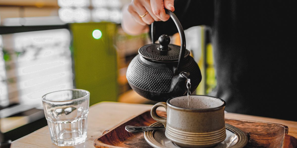 Pouring tea into a cup in a warm, quiet setting